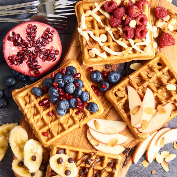 A wooden board of Buttermilk Sourdough Waffles with Protein with different toppings