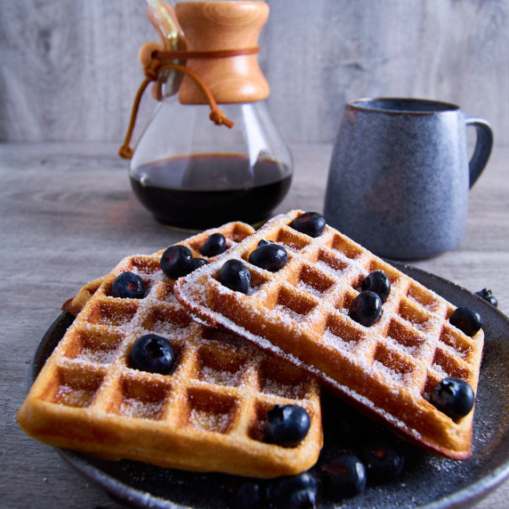 A plate with three Buttermilk Sourdough Waffles with Protein and Wholewheat. Topped with blueberries