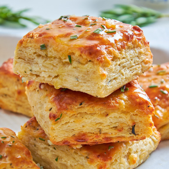 A stack of Buttery Flaky Protein Sourdough Cheese Biscuits showing the layers and specks of rosemary