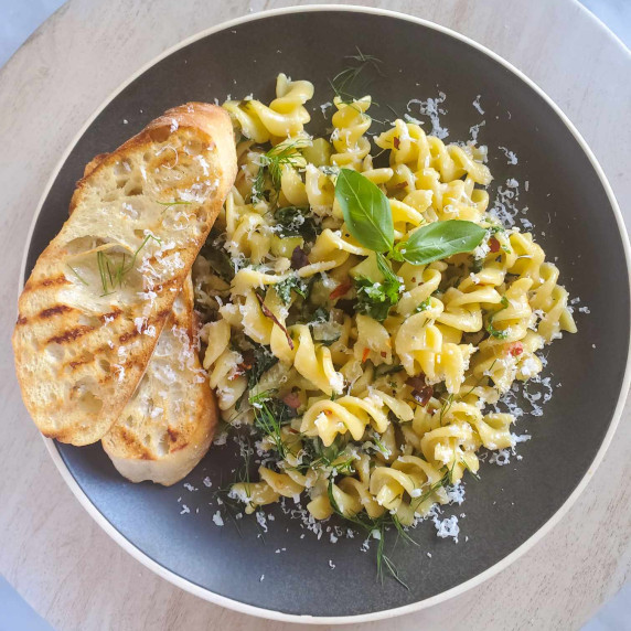 Fusilli dressed in green herbs and white cheese with grilled toast