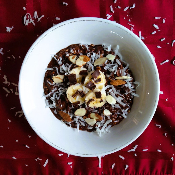 Dark chocolate oatmeal, garnished with banana, almonds, and sprinkled with coconut flakes.
