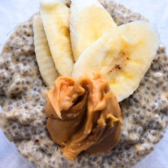Chia pudding topped with four banana slices and a scoop of peanut butter.