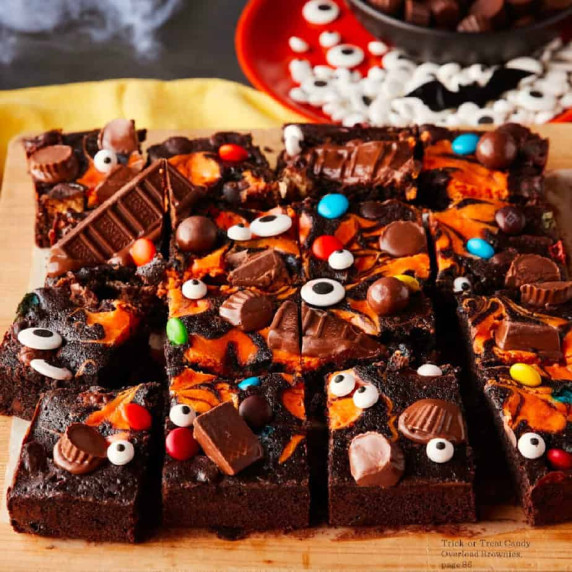 Brownies covered in an orange cream swirl, chocolate candy and candy eyes for Halloween.