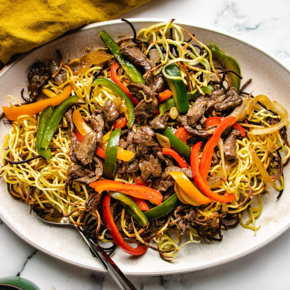 Crispy chow mein noodles, beef and red and green peppers on a white plate