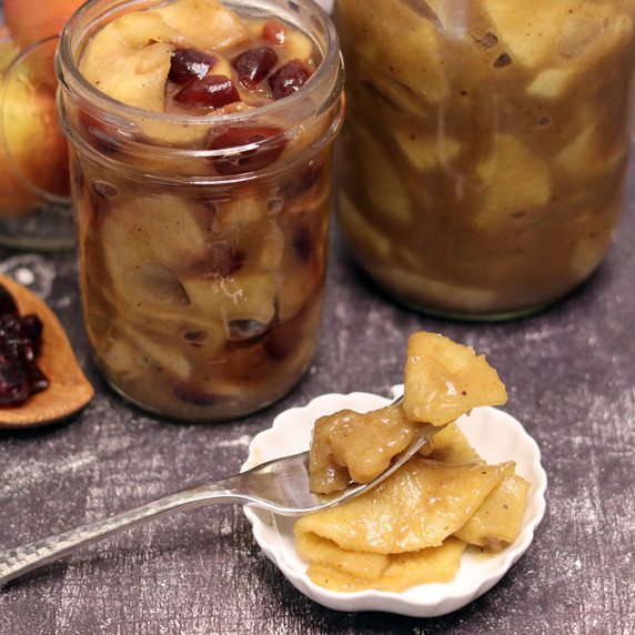 Jars of caramel apple pie filling with a small dish of caramel apple pie filling in front