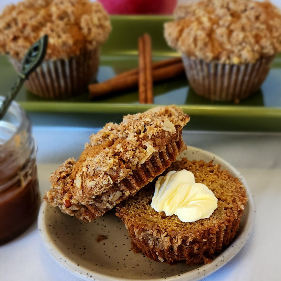 Caramel Apple Muffins with Pecan Streusel on a plate with a pat of butter.