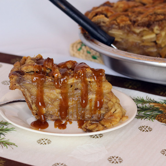 Slice of Caramel Toffee Apple Pie with caramel sauce on a white plate