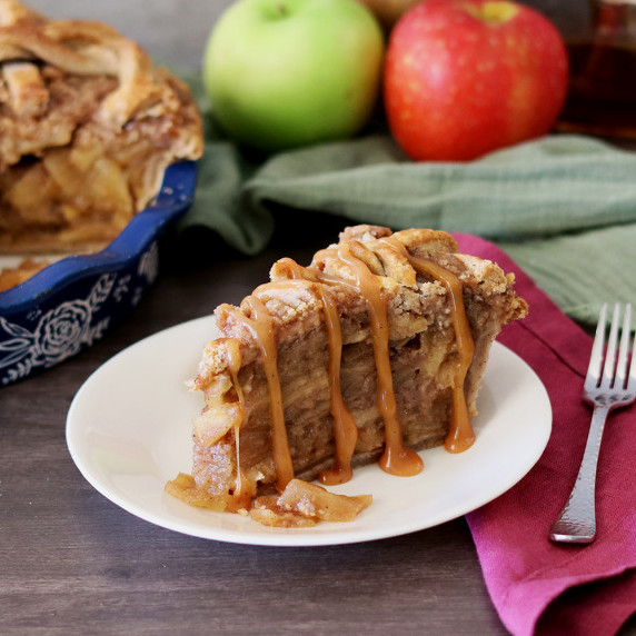 Slice of Caramel Toffee Apple Pie with caramel sauce on a white plate