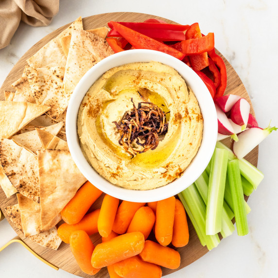 Plate of hummus with pita chips and vegetables.