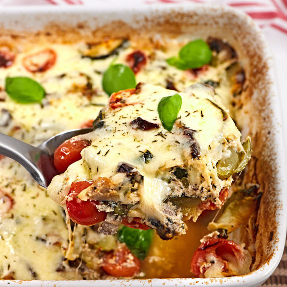 Serving of vegetable casserole with melted cheese on spoon.