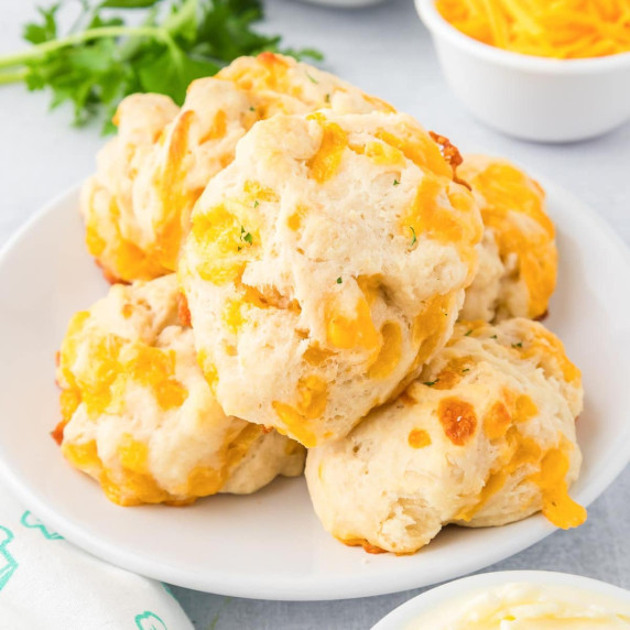 A plate of garlic cheddar cheese drop biscuits on a counter.