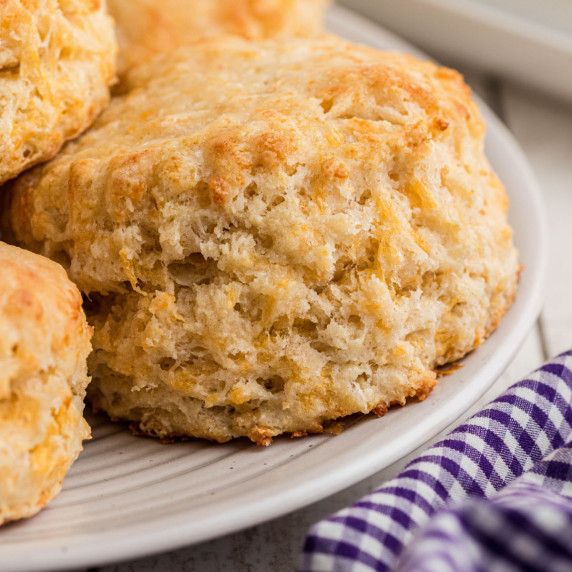 Close up of a cheddar biscuit on a plate, with others.