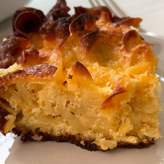 A slice of Classic Cottage Cheese Noodle Kugel on a white plate with a fork. 