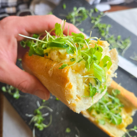 Golden baguette stuffed with fluffy eggs, melty cheddar, and green garnishes