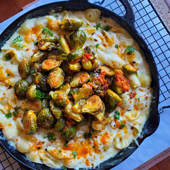 A black skillet filled with white mac and cheese and some gorgeous red & green brussel sprouts.