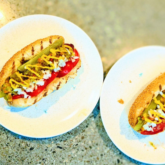 Chicago style hot dogs on plates on a concrete countertop