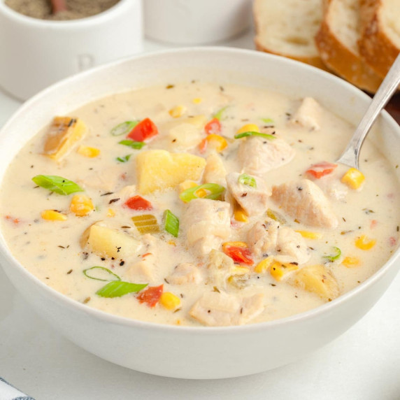 A bowl of creamy chicken corn chowder soup with potato, chicken, corn, green onion and bell pepper.