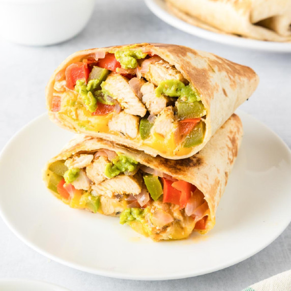 Two halved of a chicken fajita wrap cut and half and stacked to see the inside filling.
