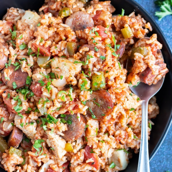 Sausage & Chicken Cajun Jambalaya RECIPE served in a black bowl with a spoon.