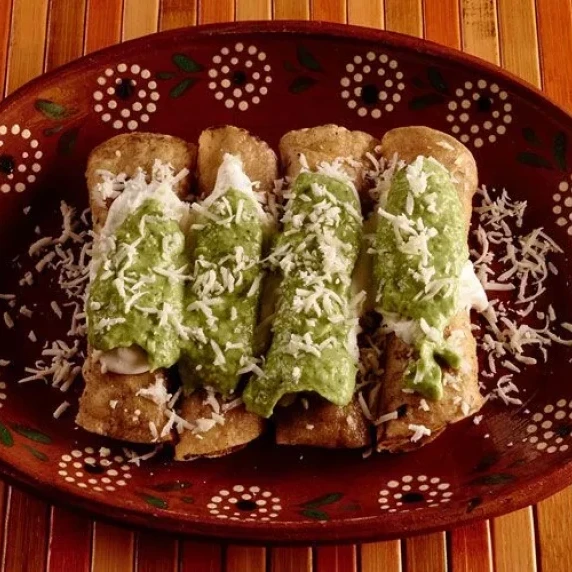 Chicken Taquitos with salsa on each with shredded queso fresco and salty fresh crumbly cheese