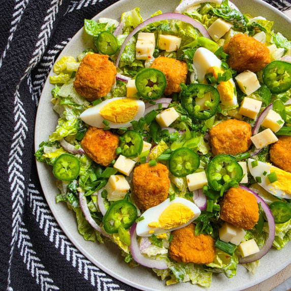 A colourful assortment of veggies and golden chik'n bites against a black towel.