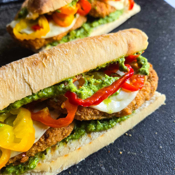 Ciabattas stuffed with golden brown chik'n, green pesto, and multi-coloured hot peppers.