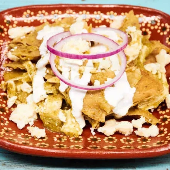 Chilaquiles Verdes with Chicken bathed in green salsa and topped with Mexican cream
