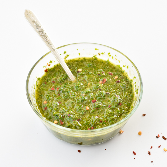 a bowl of low fodmap chimichurri sauce in a clear glass bowl with a spoon