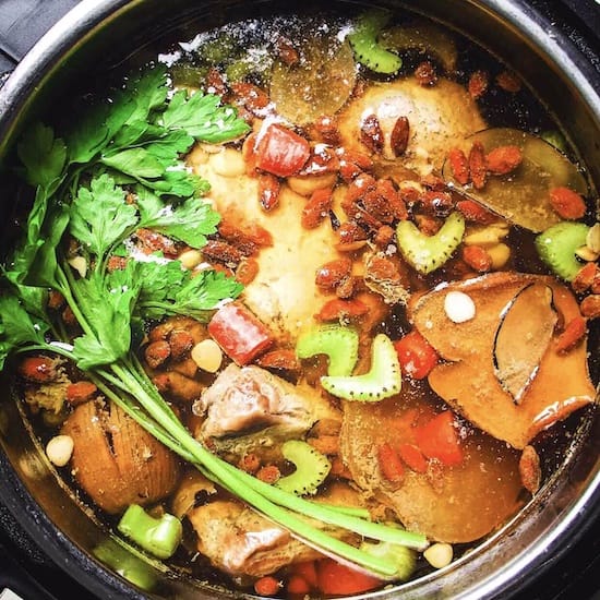 Chicken soup, carrots, celery and herbs in a metal cooking pot