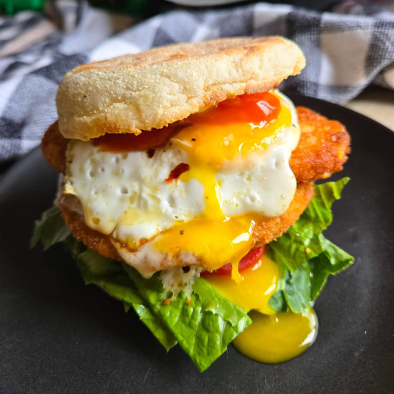 A breakfast sandwich with golden yolk cascading down the sandwich.