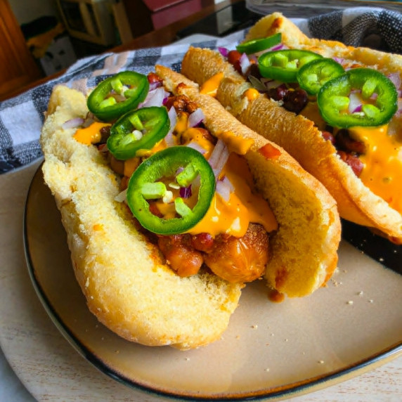 Hot dogs smothered in chili, yellow queso, and spicy green jalapenos.