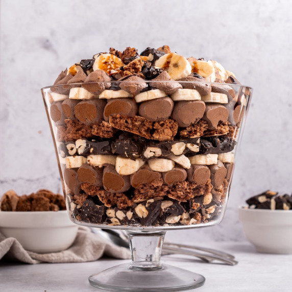 A glass bowl filled with chocolate mousse, bananas, chocolate meringue, and chocolate covered cashew