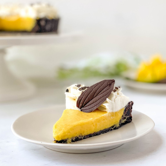 top view of whole chocolate mango tart topped with whipped cream and chocolate leaves