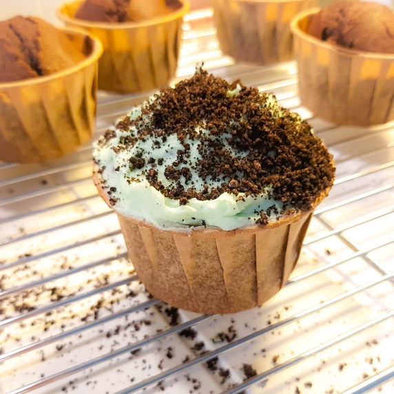Chocolate mint cupcake with green frosting and cookie dirt topping.