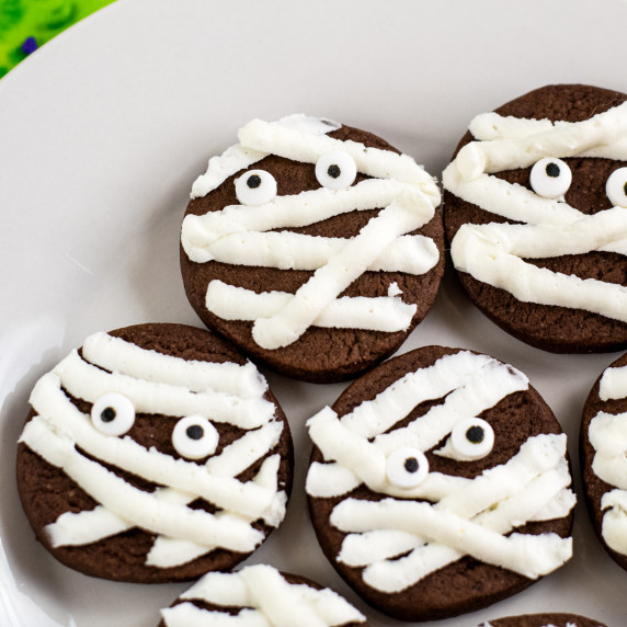 Chocolate cookies decorated to look like mummys with vanilla frosting and candy eyeballs.