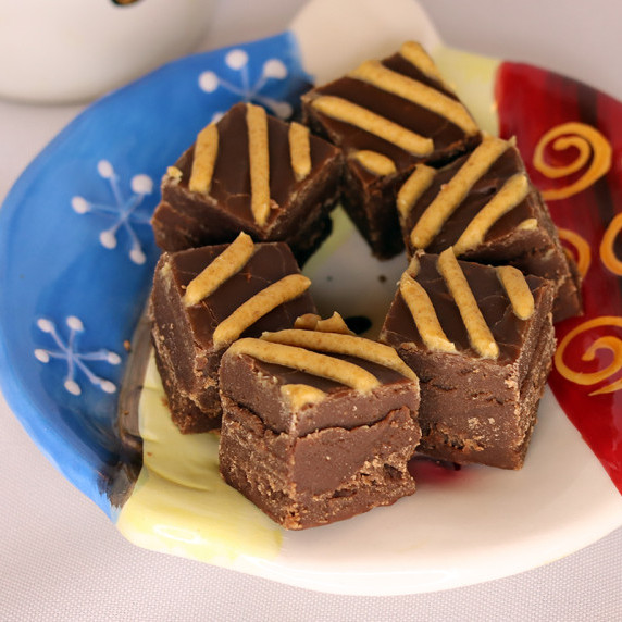 Old Fashioned Chocolate Peanut Butter Fudge arranged on a holiday plate against a white background.