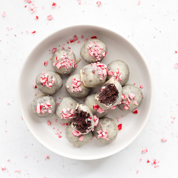 Chocolate peppermint protein balls topped with crushed candy canes on a white plate — a healthy no-b