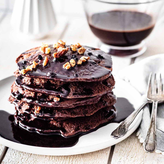 Stack of chocolate protein pancakes on a white plate.