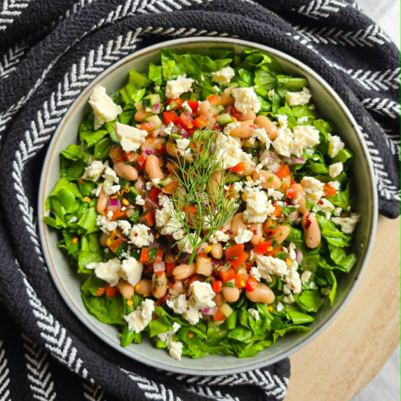 Fresh bean salad served over a bed of green romaine against a black towel.
