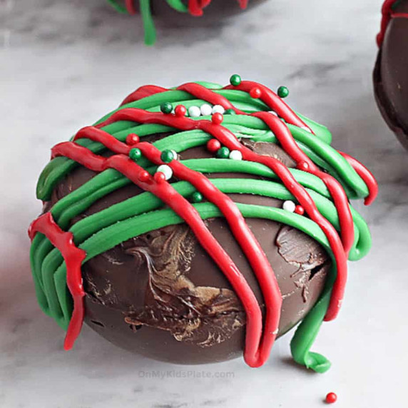Close up of a chocolate hot cocoa bomb with red and green decorations.
