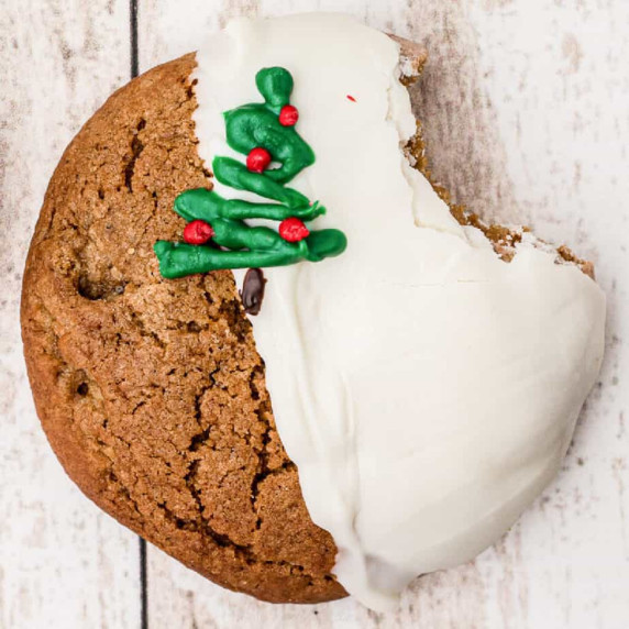 Close up of a molasses cookie dipped in white chocolate & decorated with a chocolate Christmas tree.