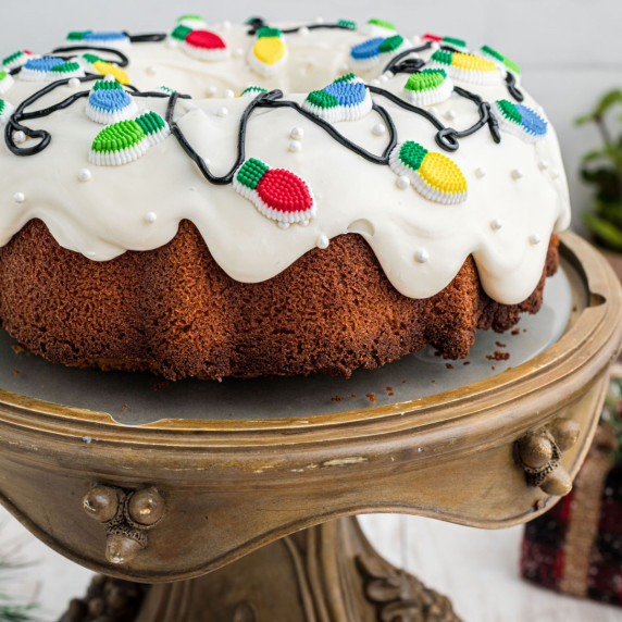 Side view of a Christmas bundt cake with christmas lights on top.