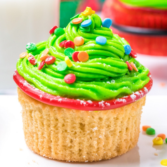 Vanilla cupcake topped with green frosting and candies to mimic a Christmas tree