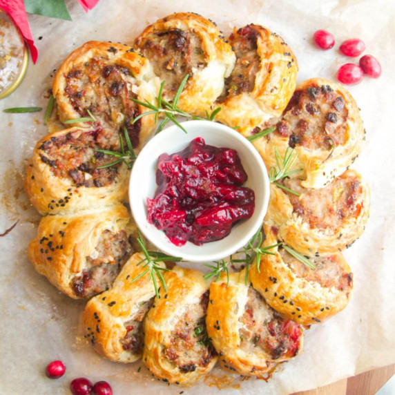 Sausage rolls in a circle, with cranberry sauce in the middle.