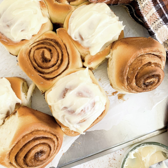 cinnamon rolls with cream cheese frosting on a baking sheet