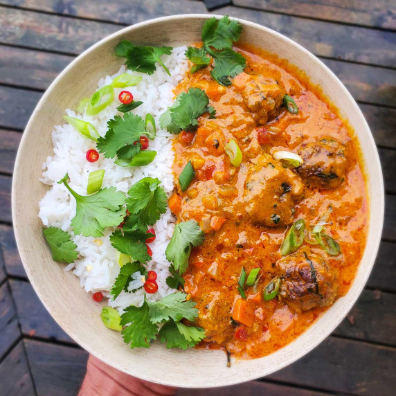 Gorgeous orange meatball curry served with white basmati rice and green herbs.