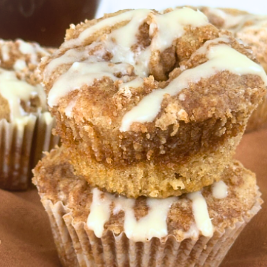 Stacked close-up two Coffee Cake Muffins with cinnamon streusel topping and vanilla icing drizzle.