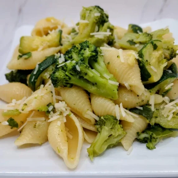 Mini shell pasta sauteed with garlic, olive oil, zucchini, and broccoli and served with grated chees