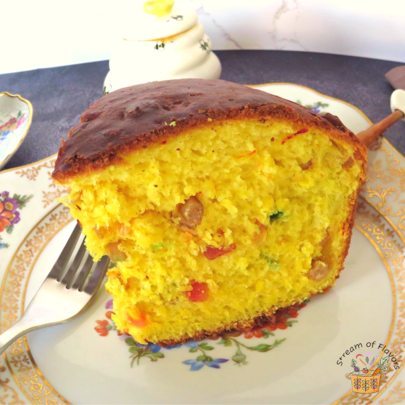 Cornish saffron cake on a cake plate with a honey pot and a cup of tea and fork