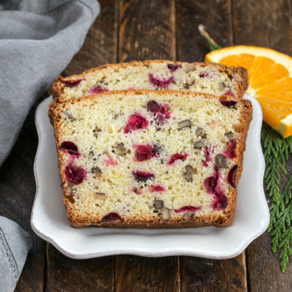 Two slices of cranberry pecan bread on a square white plate.